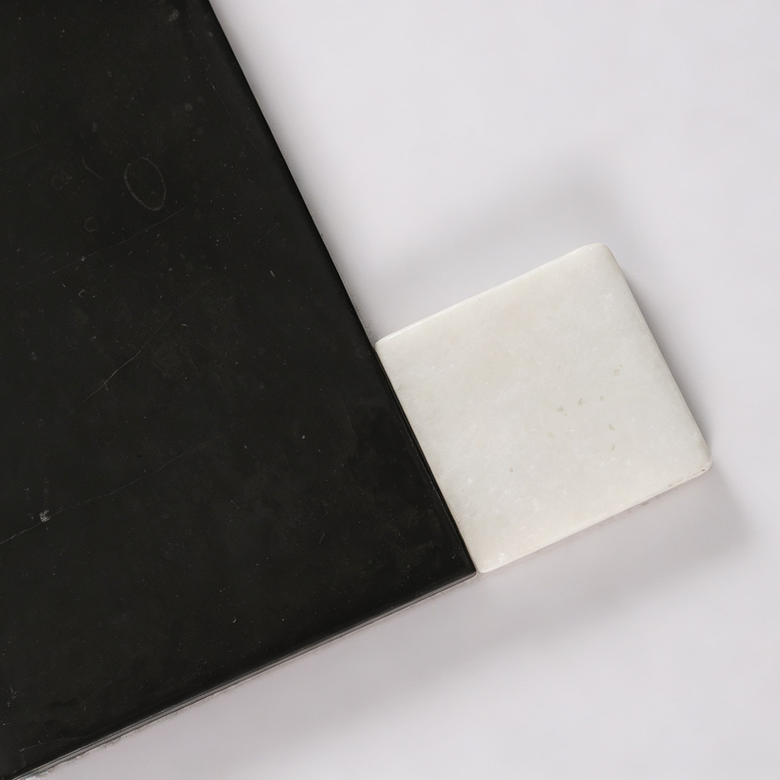 Close-up detail of white square accent on black marble mosaic tile