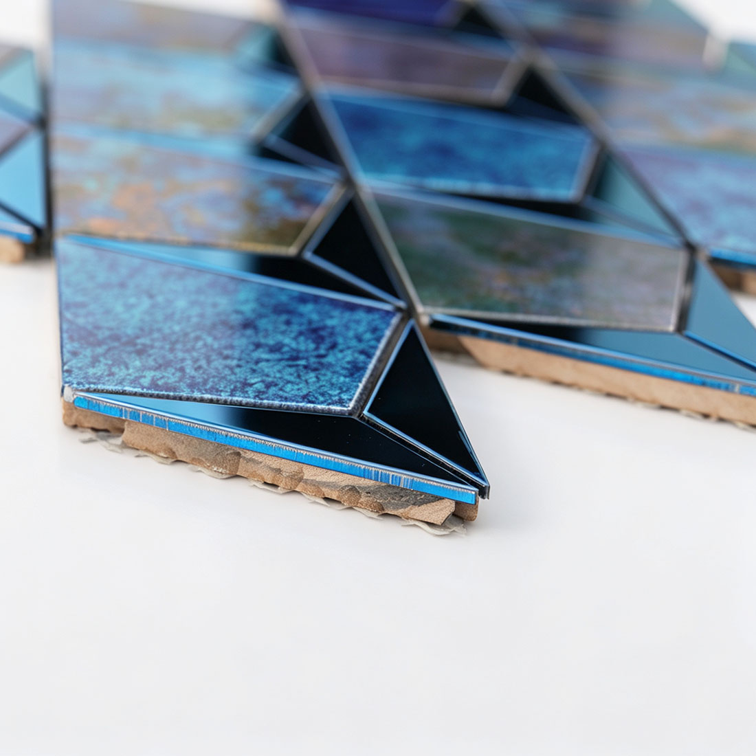 Side view of blue antique kite-shaped metal mosaic tiles showing the tile base