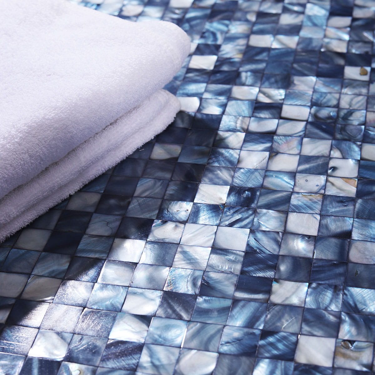 Close-up of blue shell mosaic tiles with a folded white towel on top