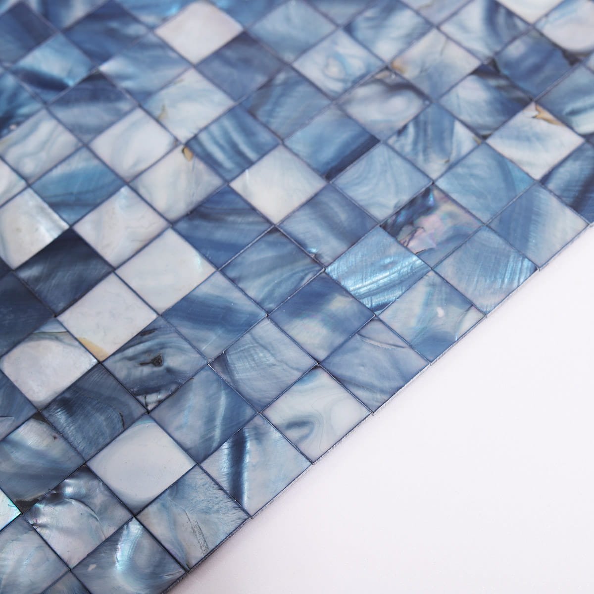 Close-up view of a blue natural shell mosaic tile sheet showing iridescent square pieces