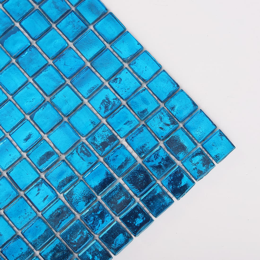 Corner close up of bright blue square glass mosaic tile sheet