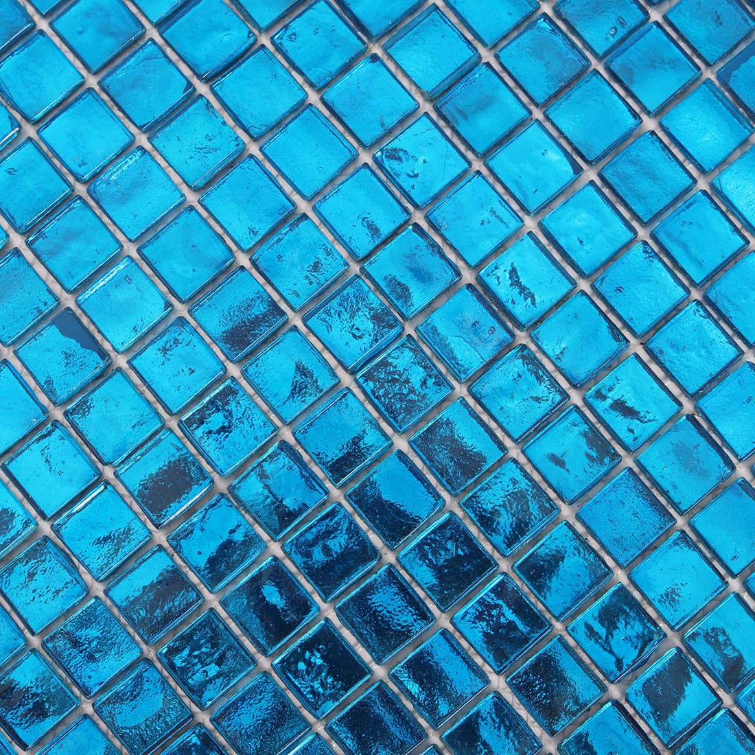 Surface detail of bright blue square glass mosaic tile in diagonal view
