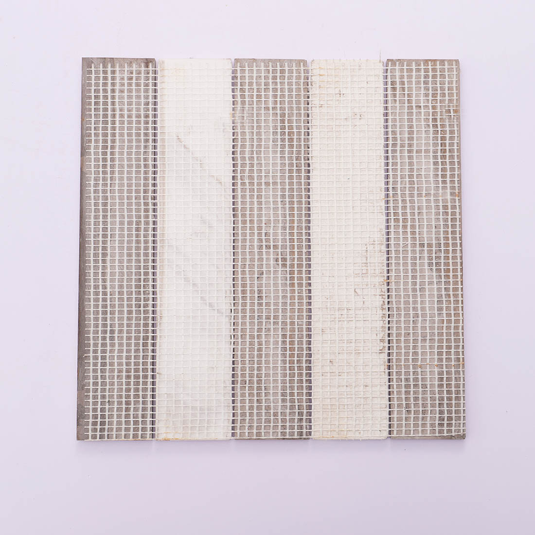 Back view of brown and white linear marble mosaic tile with mesh backing.