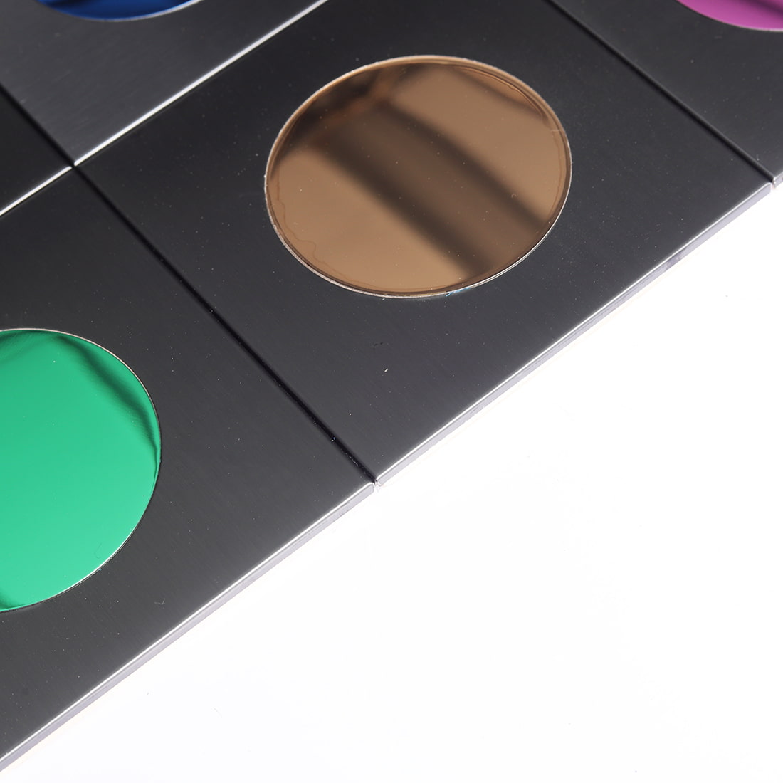 Corner detail of brushed black square tile with bronze reflective round inset