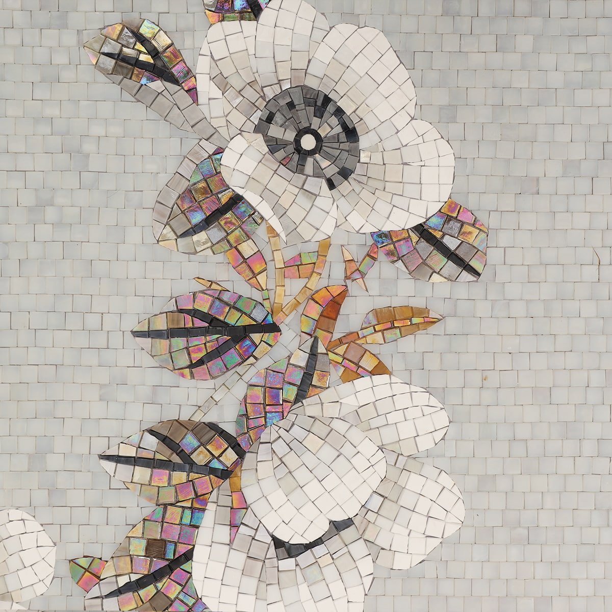 White mosaic flower with iridescent glass leaves on a tiled background.