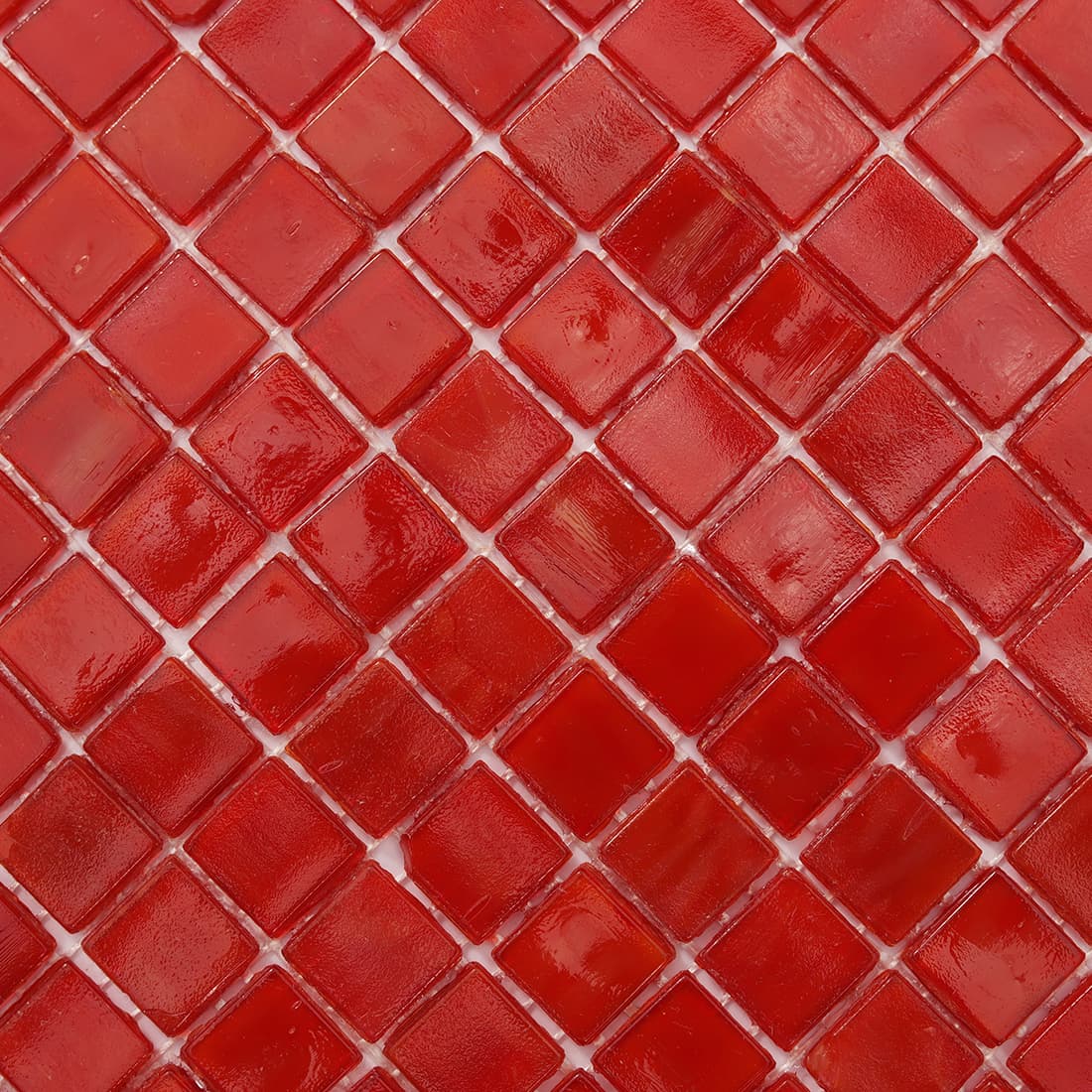 Close up of cherry red square glass mosaic tile showing varied glossy textures