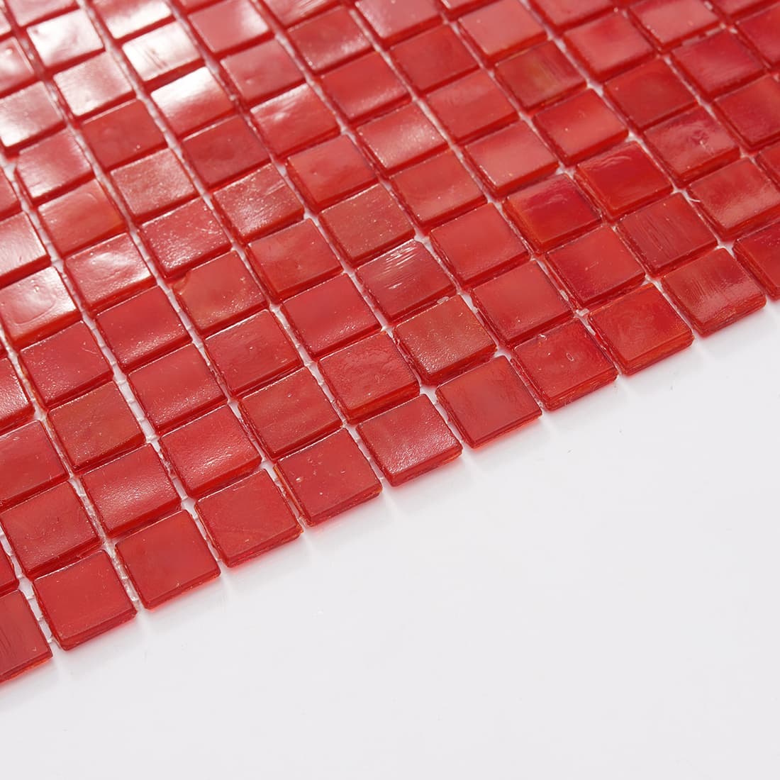 Edge detail of cherry red square glass mosaic tile sheet on white background