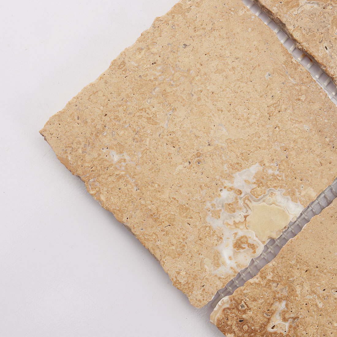 Close up of beige square limestone tile with natural stone markings