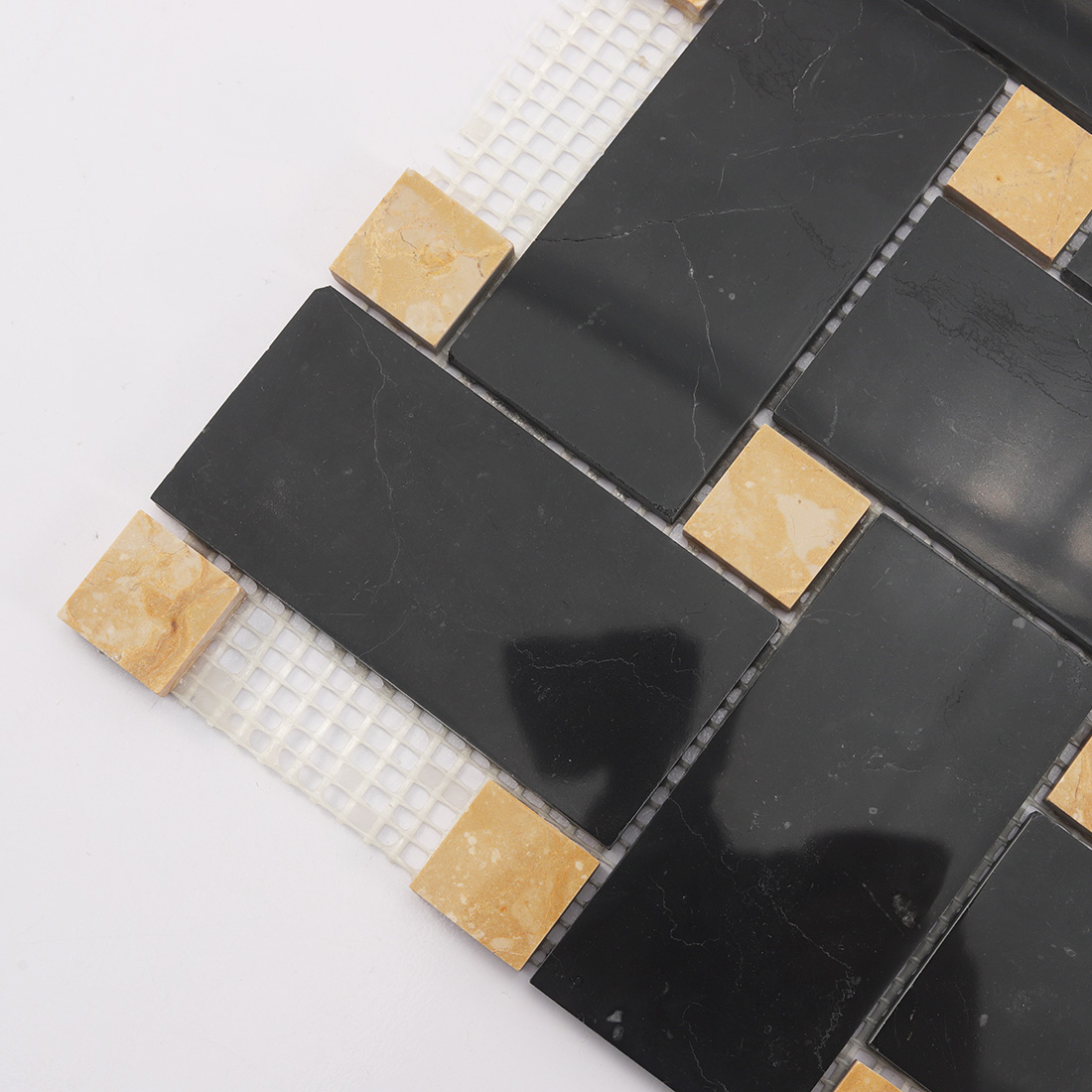 Close up of black marble basketweave tile with yellow marble dot inserts