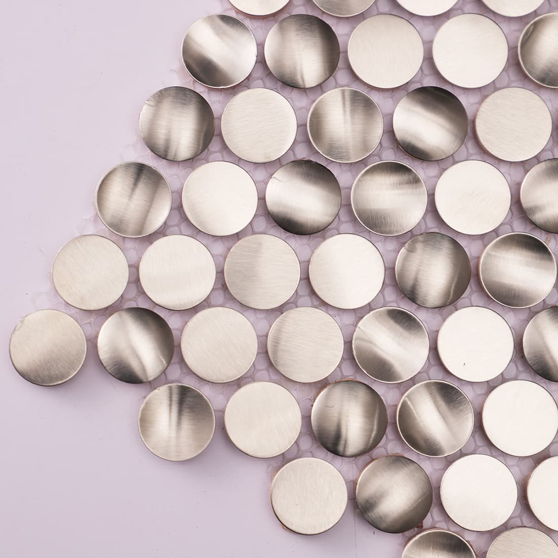 Close up of brushed silver round metal tile with soft reflective finish