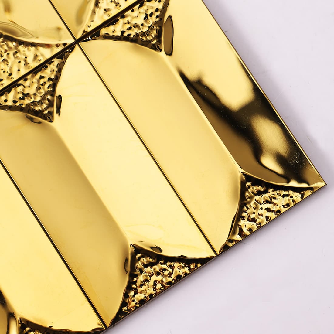 Close-up angled view of glossy gold beveled stainless steel tiles.