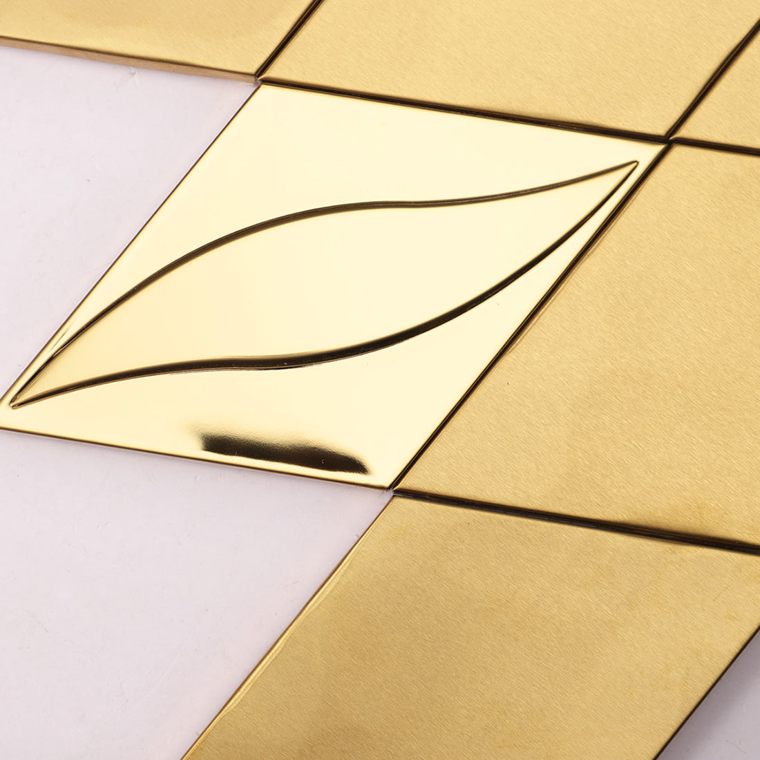 Close-up of a gold metal diamond tile featuring a 3D leaf design.