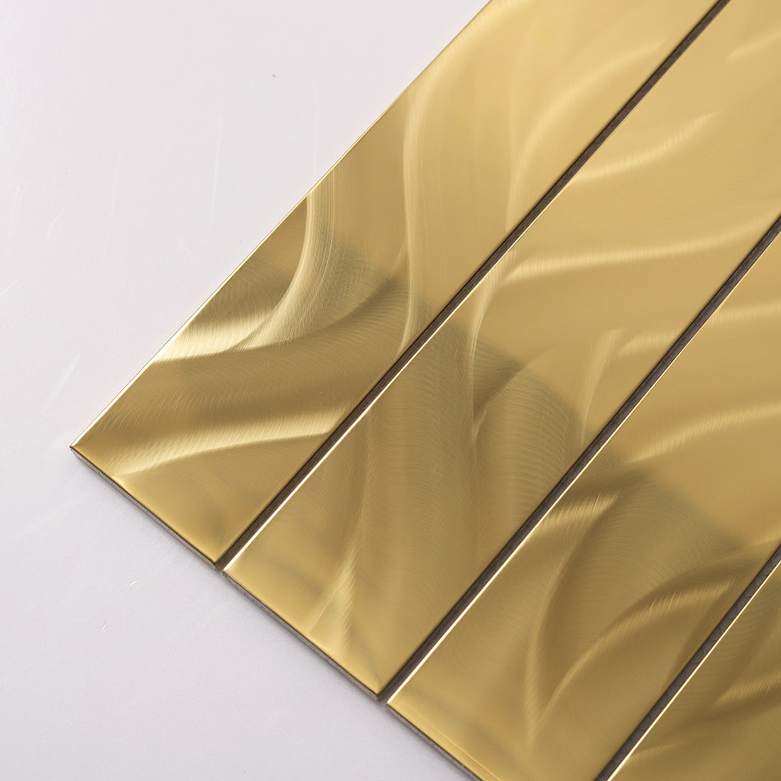 Diagonal close-up of gold stainless steel strips with a 3D flowy texture.