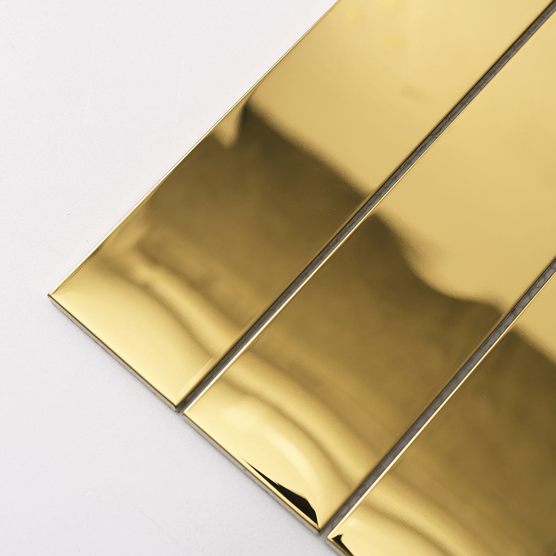 Close-up of reflective gold glossy stainless steel linear tile strips.