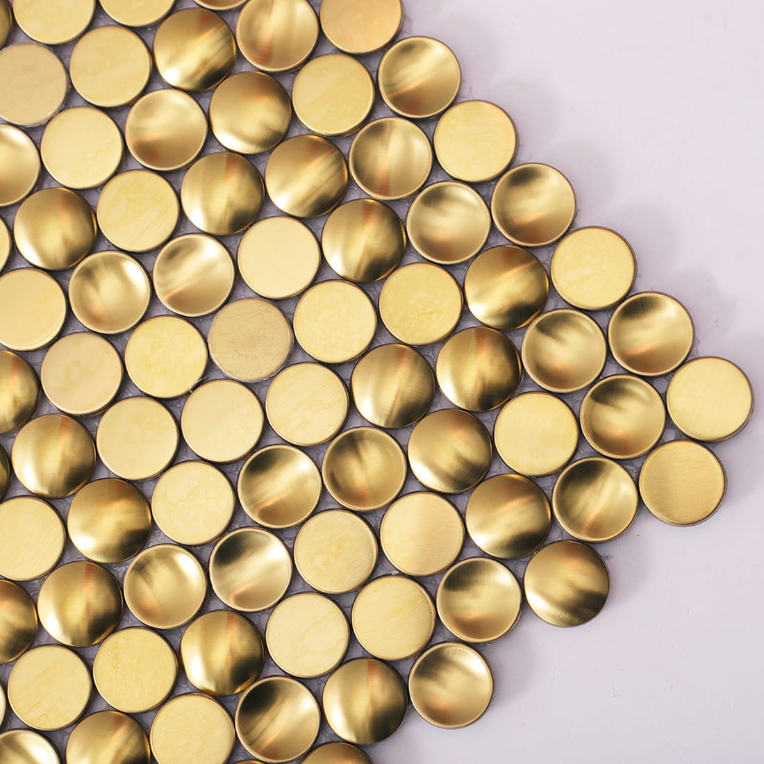 Close up of mixed texture gold metal penny round mosaic tiles.