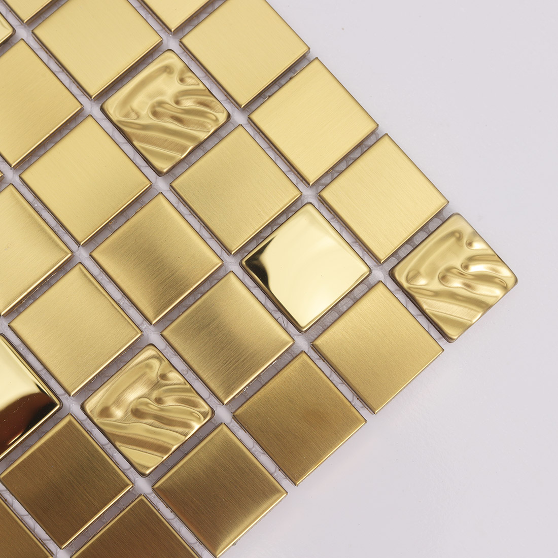 Close up of gold metal square mosaic tiles with brushed and wavy glossy pieces