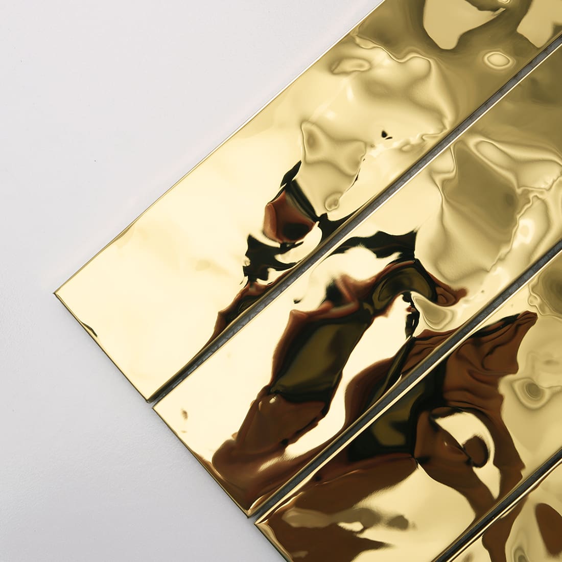 Diagonal close-up of shiny gold water ripple metal tile strips.