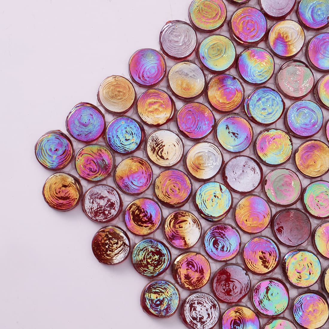 Macro shot of red glass penny tiles showing a shimmering oil slick iridescent finish.