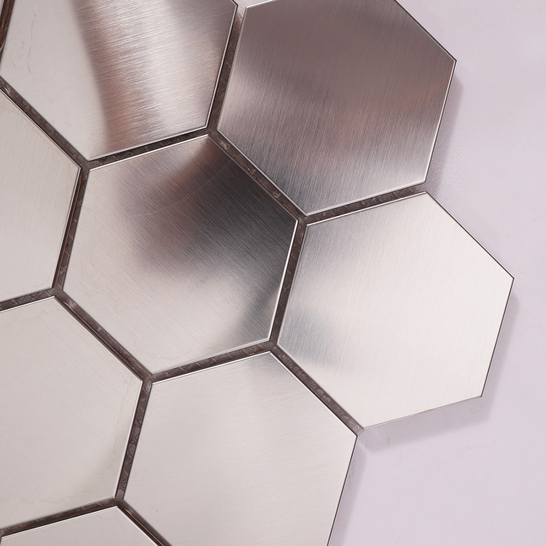 A close-up shot showing the brushed texture and reflective surface of silver hexagon tiles.