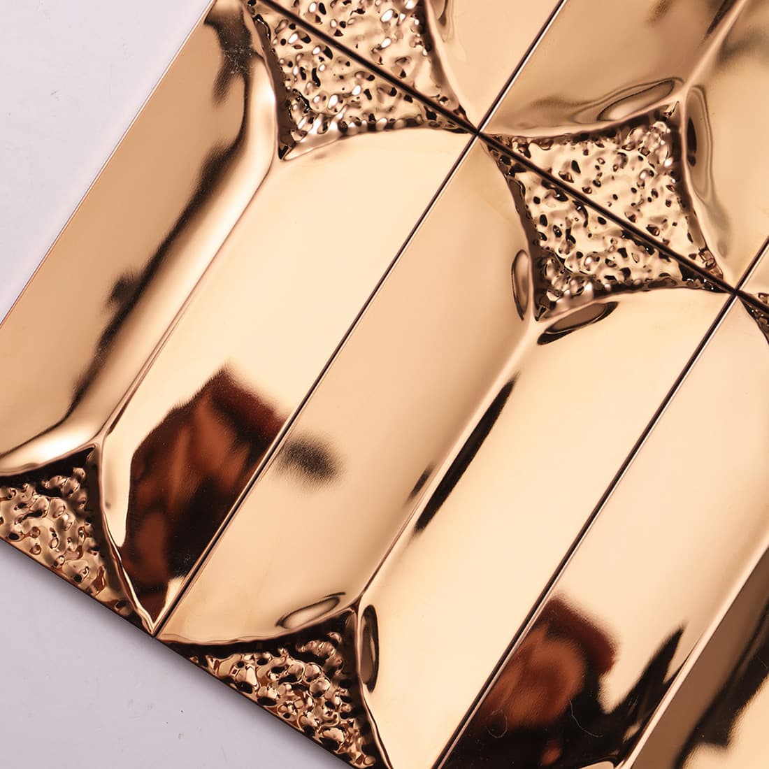 Close-up angled view of reflective rose gold beveled stainless steel tiles.