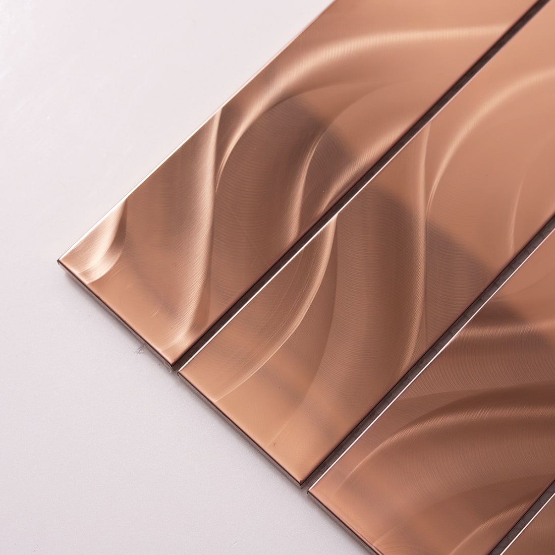 Close-up diagonal shot of rose gold stainless steel strips with flowy texture.