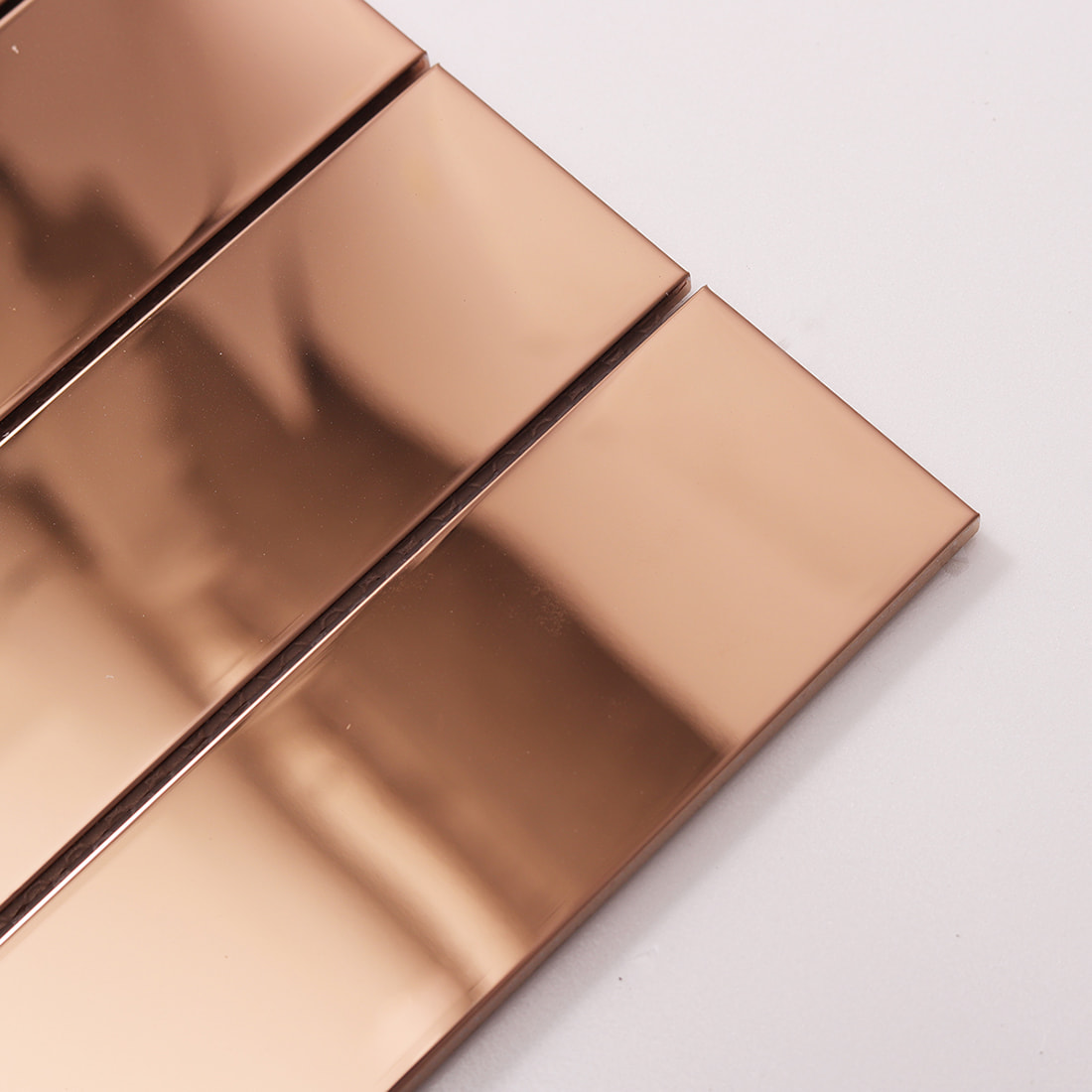 Close-up of reflective rose gold glossy stainless steel linear tile strips.