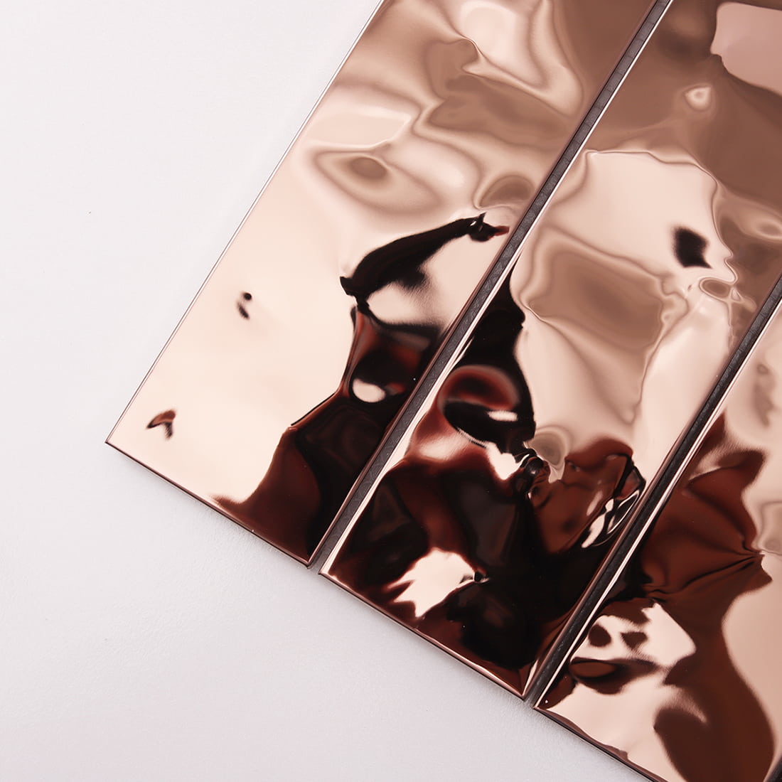 Close-up diagonal shot of reflective rose gold water ripple metal strips.