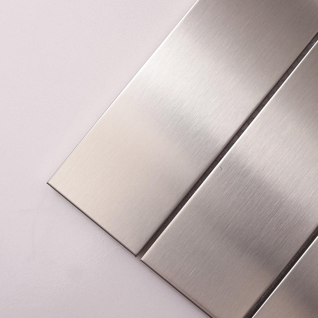 Close-up diagonal view of silver brushed linear metal tile strips.