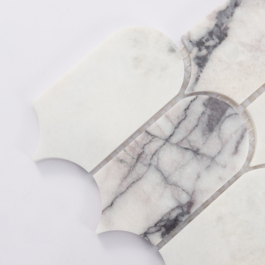 Close up of white arched marble tile with gray veining and rounded top
