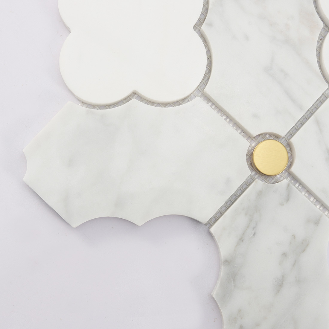 Close up of white marble arabesque tile with round gold metal insert