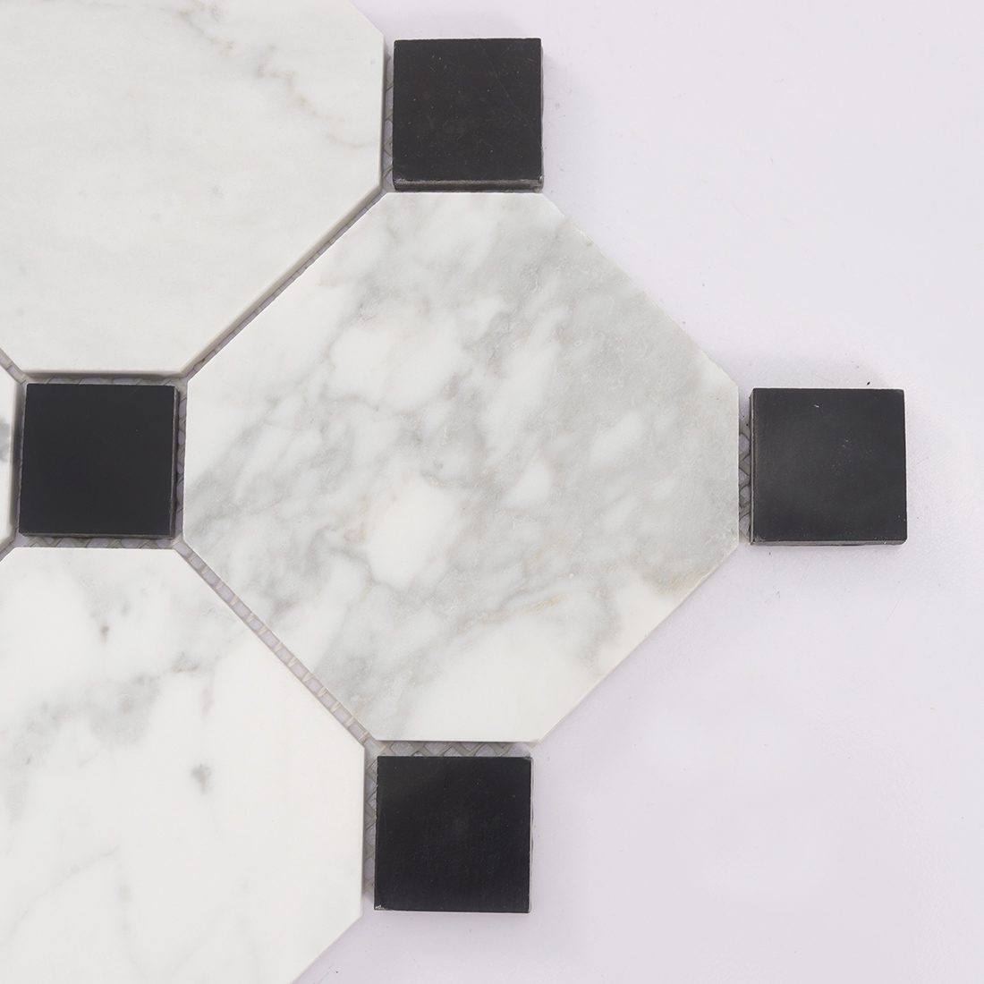 Close up of white marble octagon tile with black dot accents and gray veins