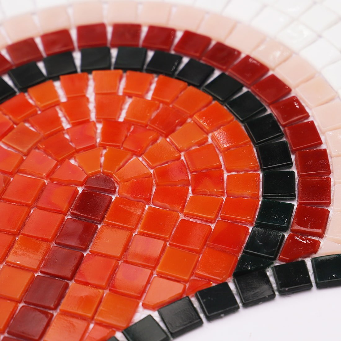 Close-up of handmade red and black glass mosaic tile in a fan pattern.