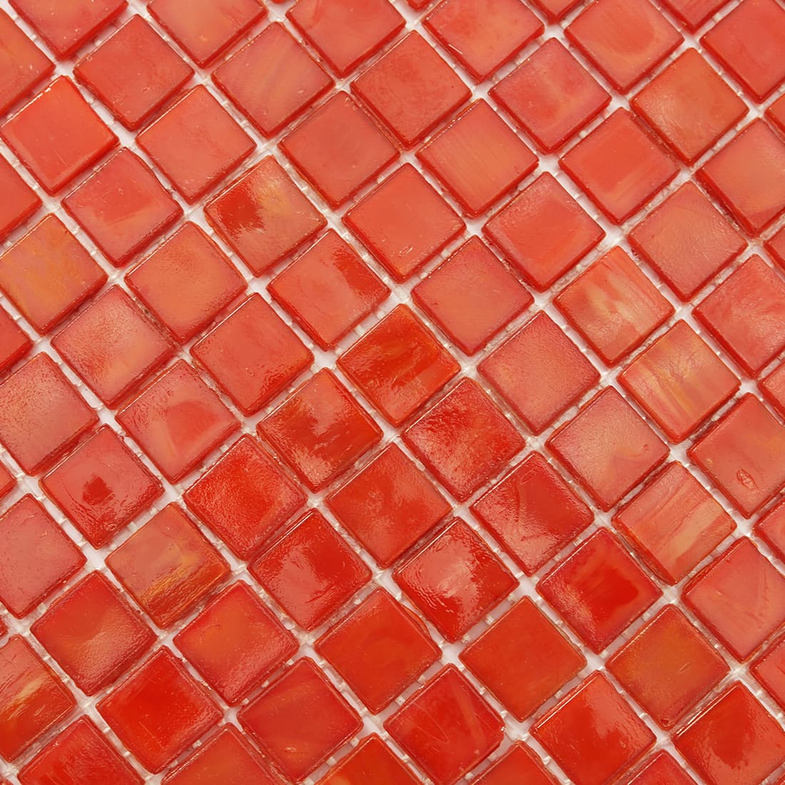 Surface detail of coral red square glass mosaic with tonal variation