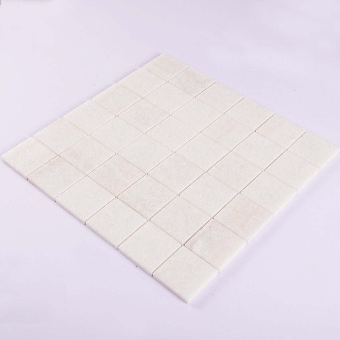 Angled view of cream square marble mosaic tile sheet