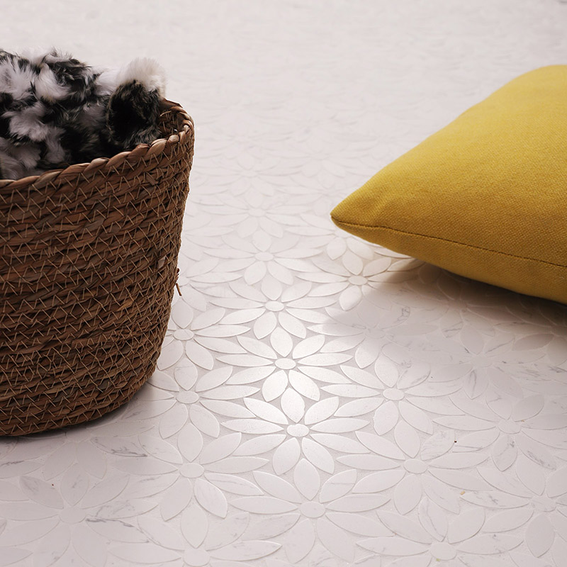Angle shot of interlocking daisy pattern white marble mosaic tiles, next to a woven basket.