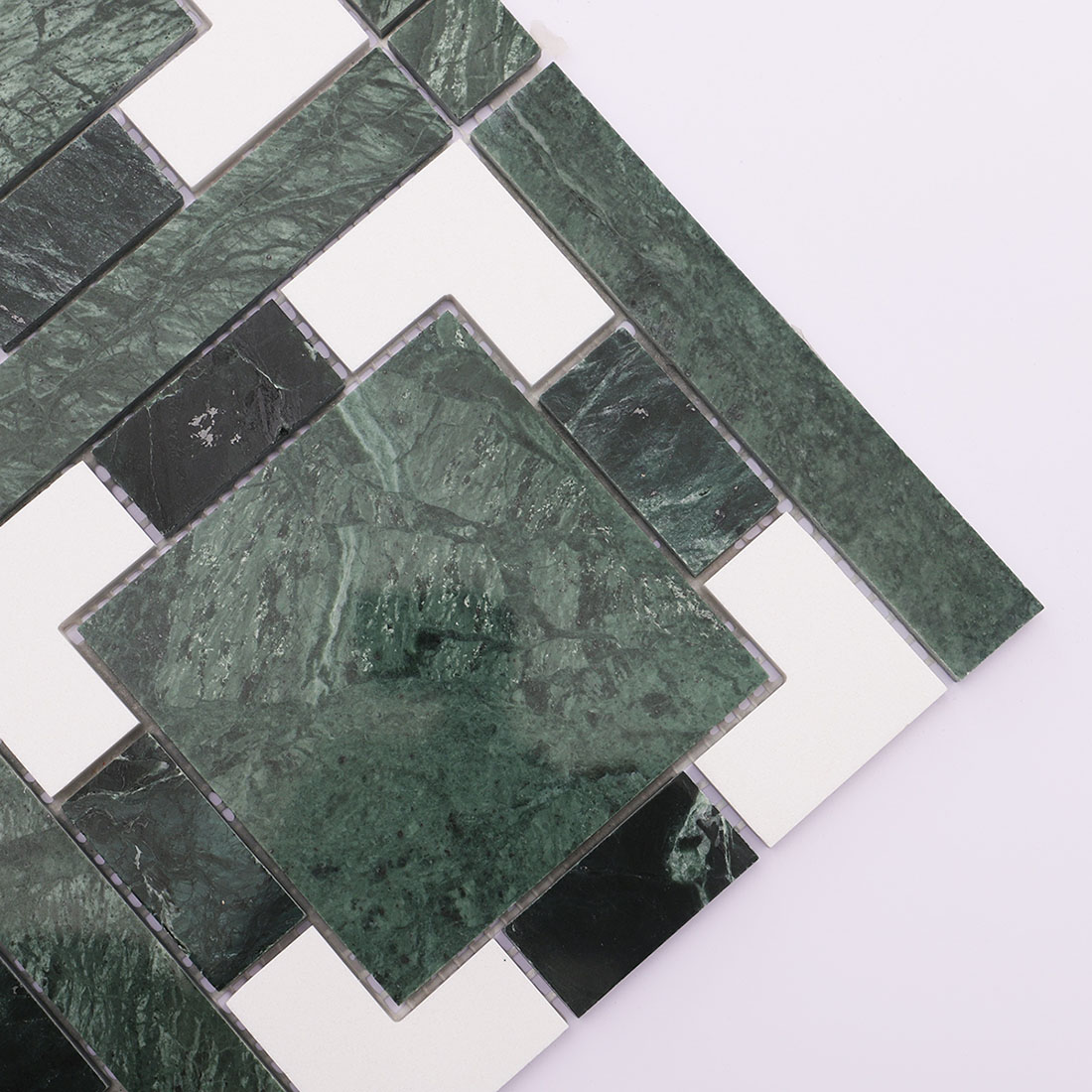 Dark green and white geometric marble mosaic tile corner close-up.