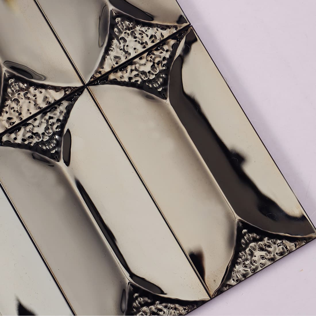 Close-up angled view of black glossy beveled stainless steel tiles.