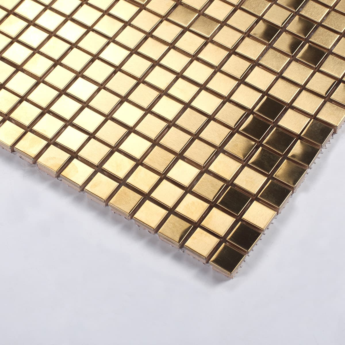 A close-up angled shot showing the reflective and brushed texture of gold square tiles.