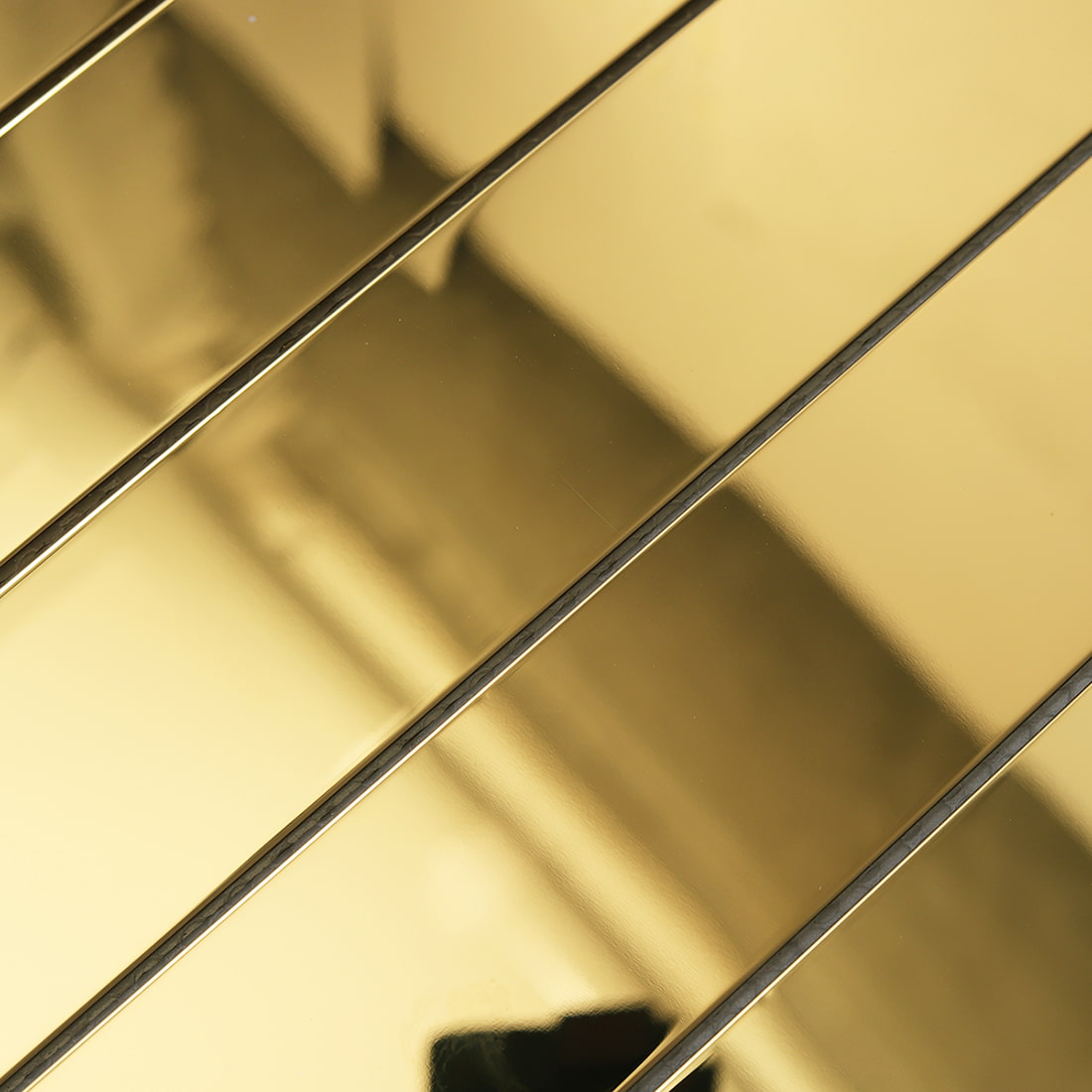 Macro shot of the reflective surface on gold linear metal tiles.