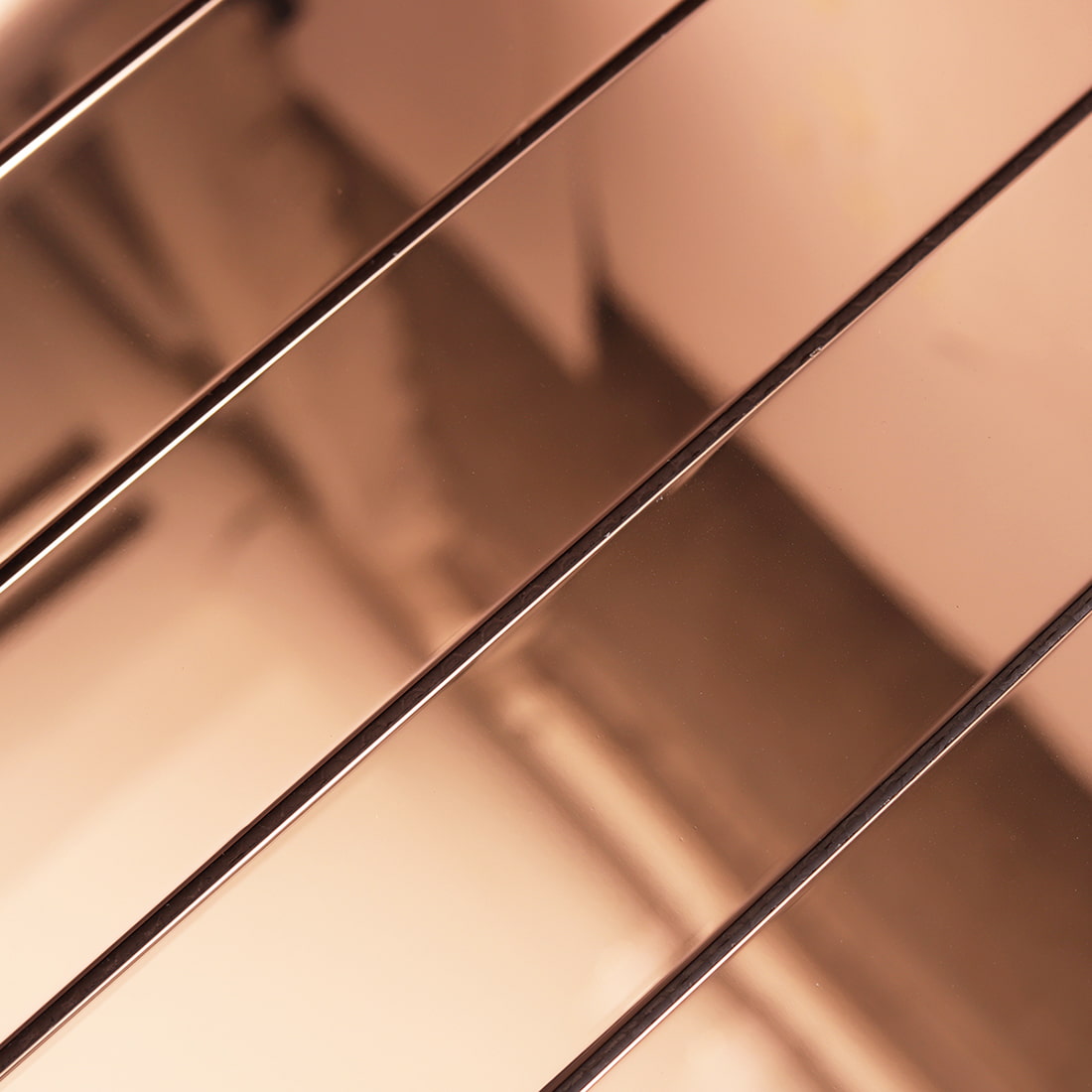 Detailed macro shot of the reflective surface on rose gold linear metal tiles.