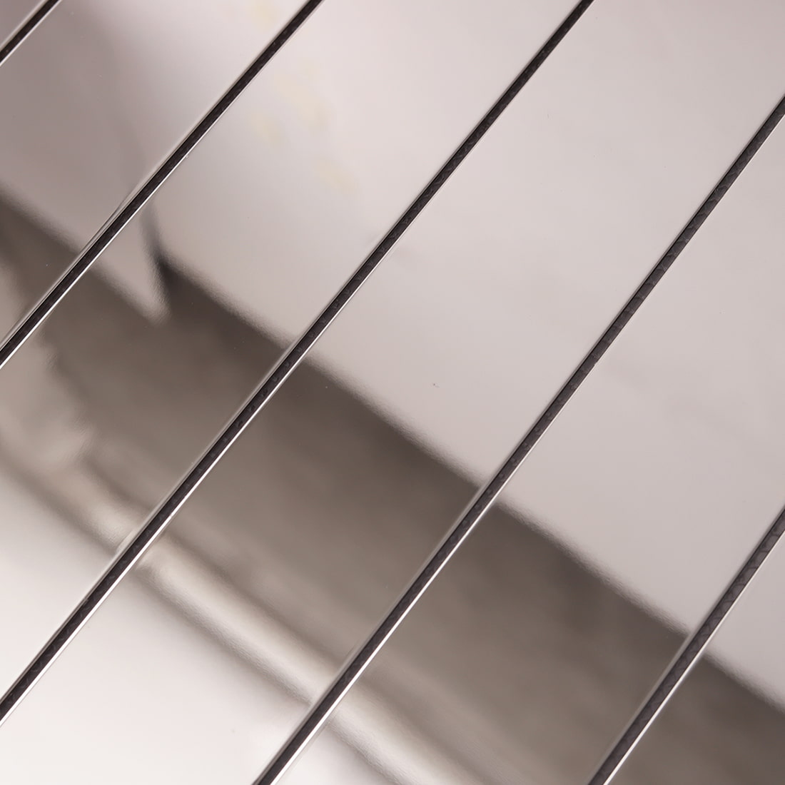 Detailed view of polished silver linear stainless steel tile surface.