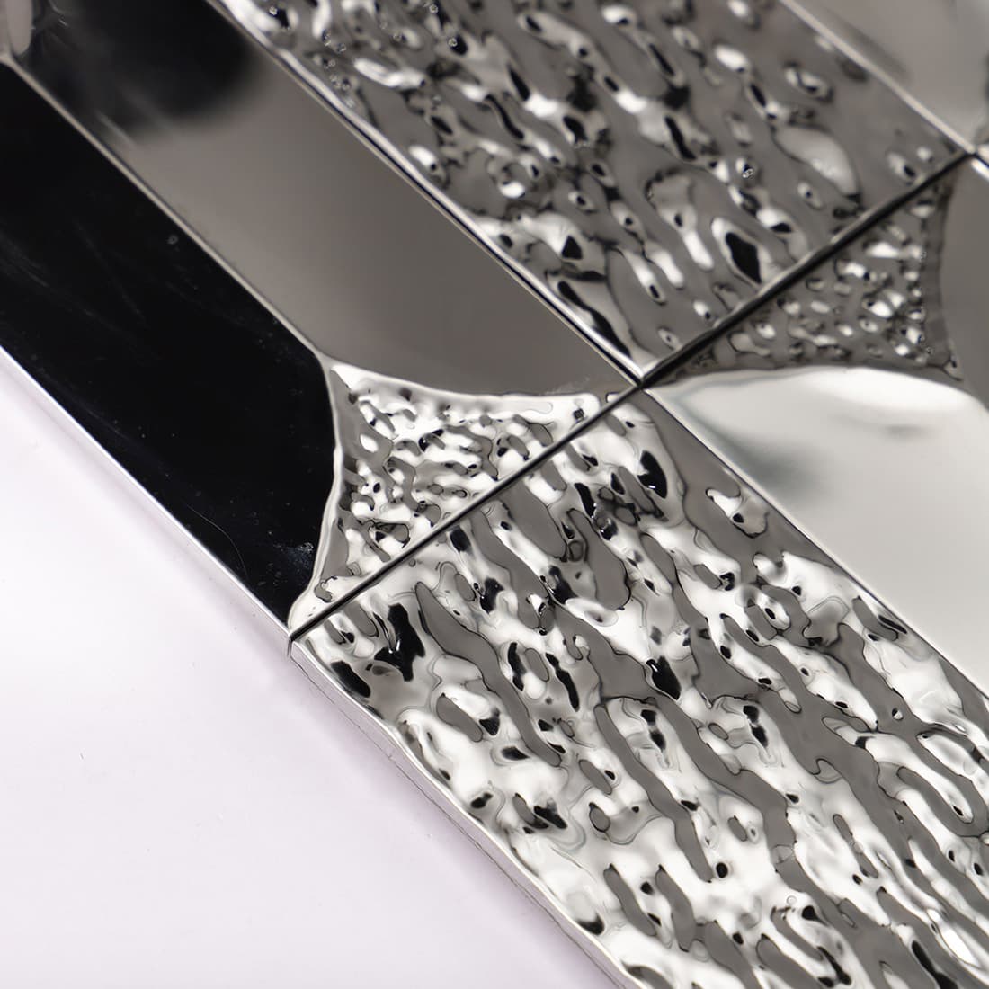 Detailed shot of the hammered texture on the corners of silver 3D tiles.