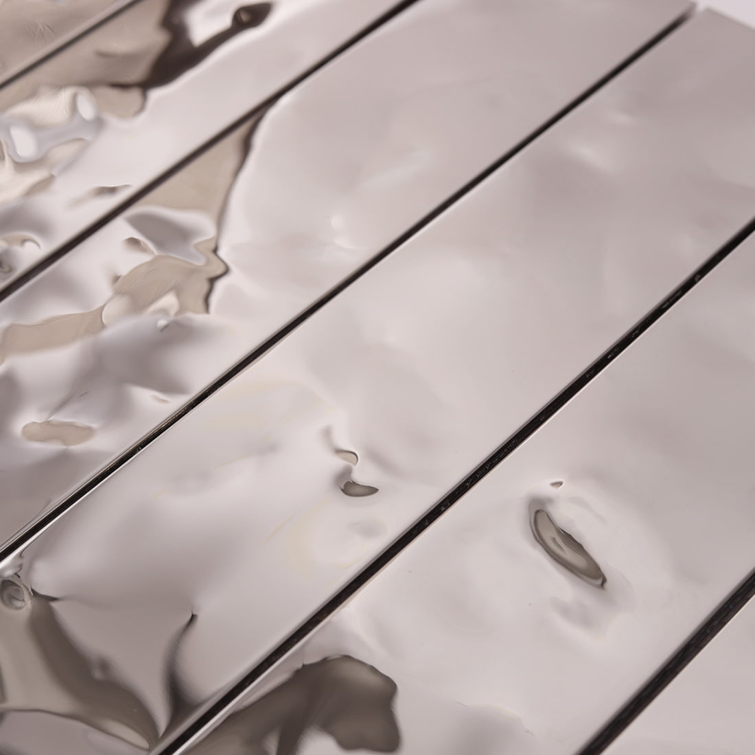 Detailed shot of the 3D water ripple texture on silver linear tiles.