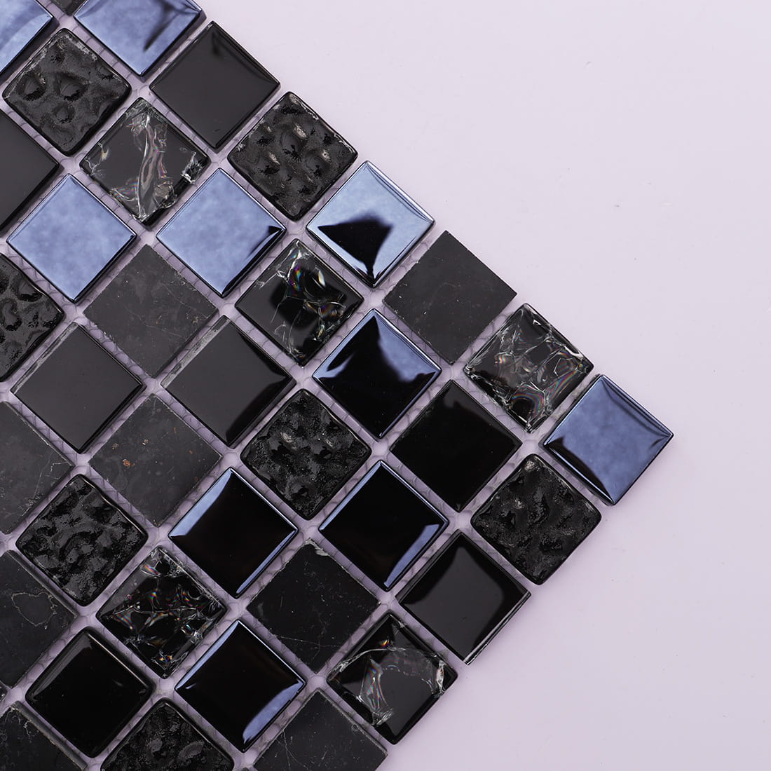 Diagonal close up view highlighting textures of glossy black glass stone mosaic.