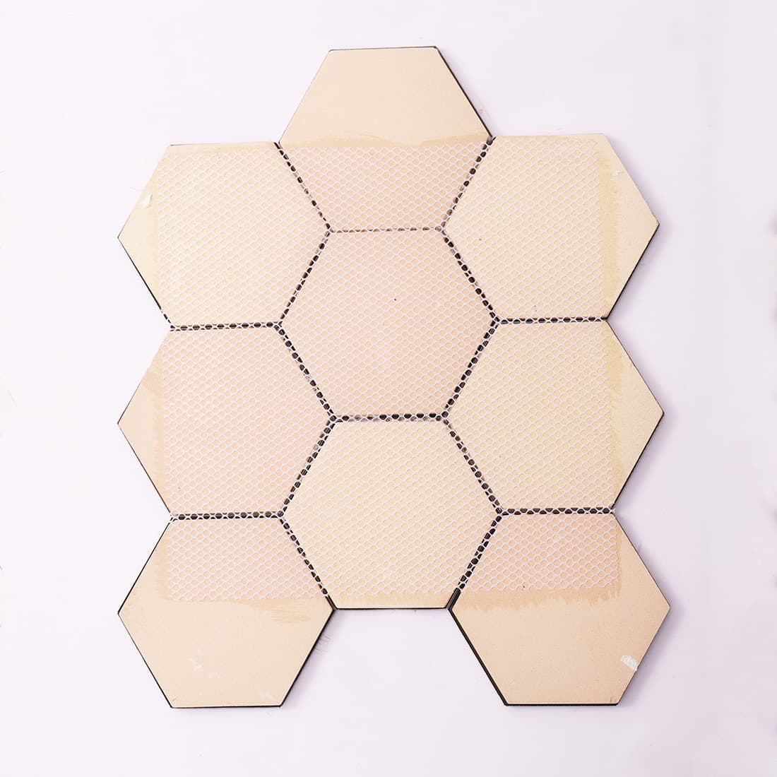 Fiber mesh backing of the rose gold and black hexagon mosaic tile sheet.