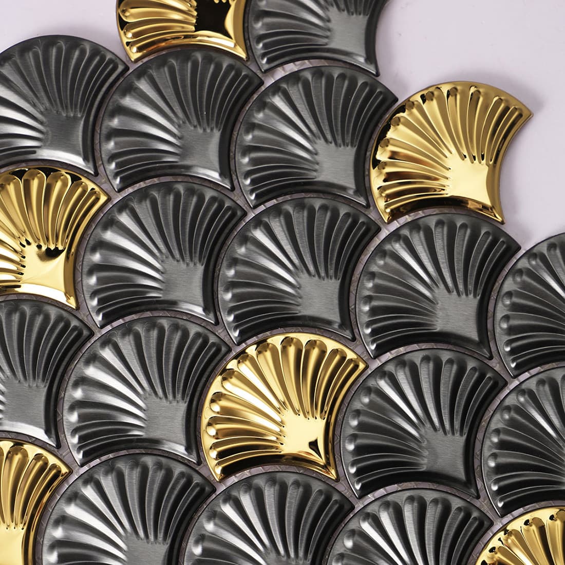 Close-up of fluted charcoal and gold fish scale mosaic tiles showing ribbed texture.