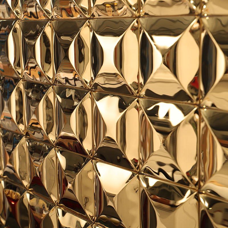 Close-up of glossy gold 3D diamond-shaped metal wall tiles, reflecting light