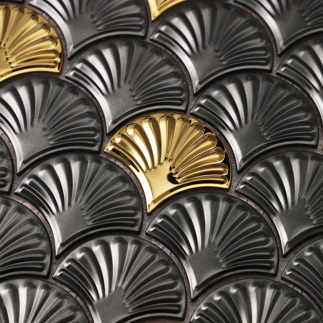 Detail of a gold accent piece among black ribbed fan shaped mosaic tiles.