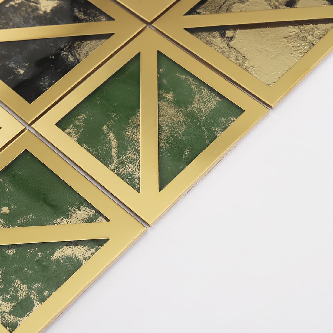 Edge detail of square mosaic tile with gold border and green textured glass