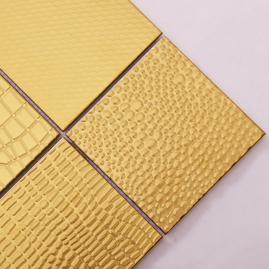 Close-up of gold embossed square metal mosaic tiles with geometric textures
